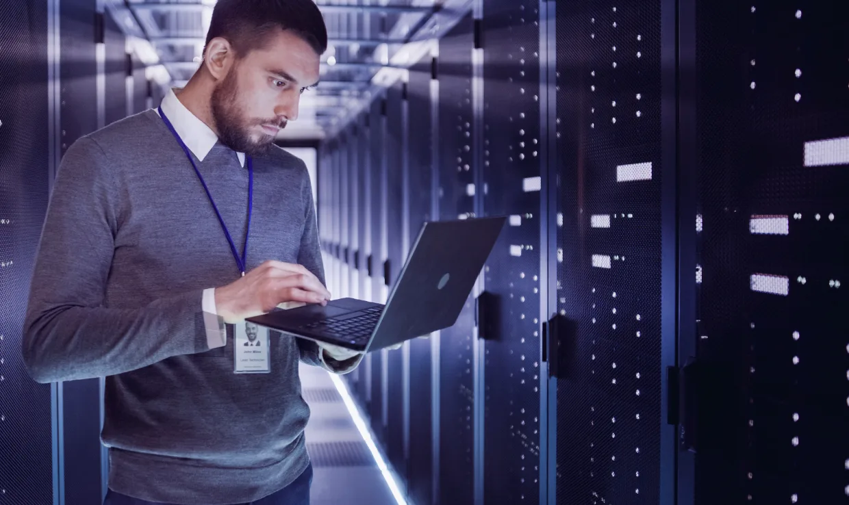 Man using a computer surrounded by IT solutions for telecommunications.